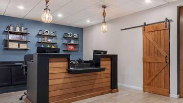 Un mostrador de recepción con detalles de madera, una pared azul con estantes que exhiben diversos objetos y una gran puerta de madera.