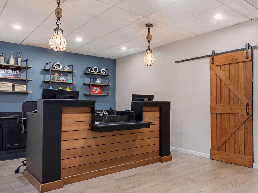 Un mostrador de recepción con detalles de madera, una pared azul con estantes que exhiben diversos objetos y una gran puerta de madera.