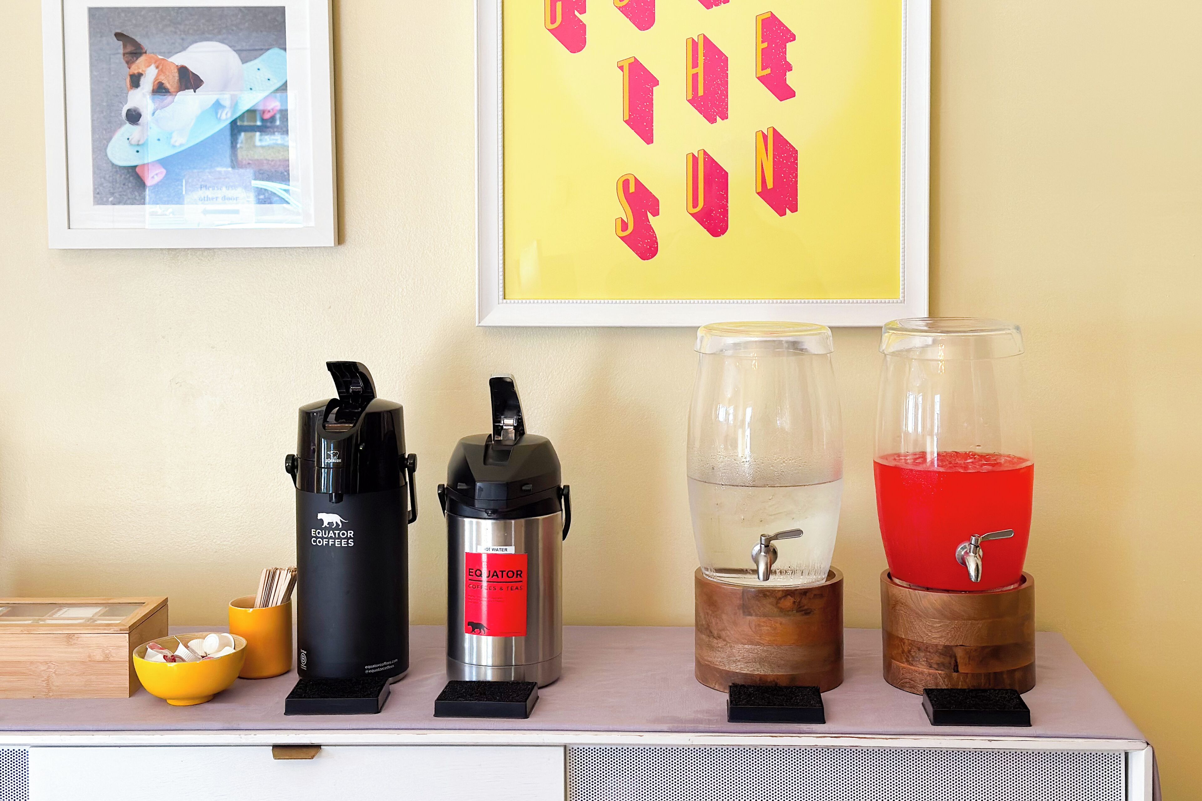 Ein Kaffee-Bereich mit zwei Espressomaschinen, einem Wasserspender und einer Obstschale.