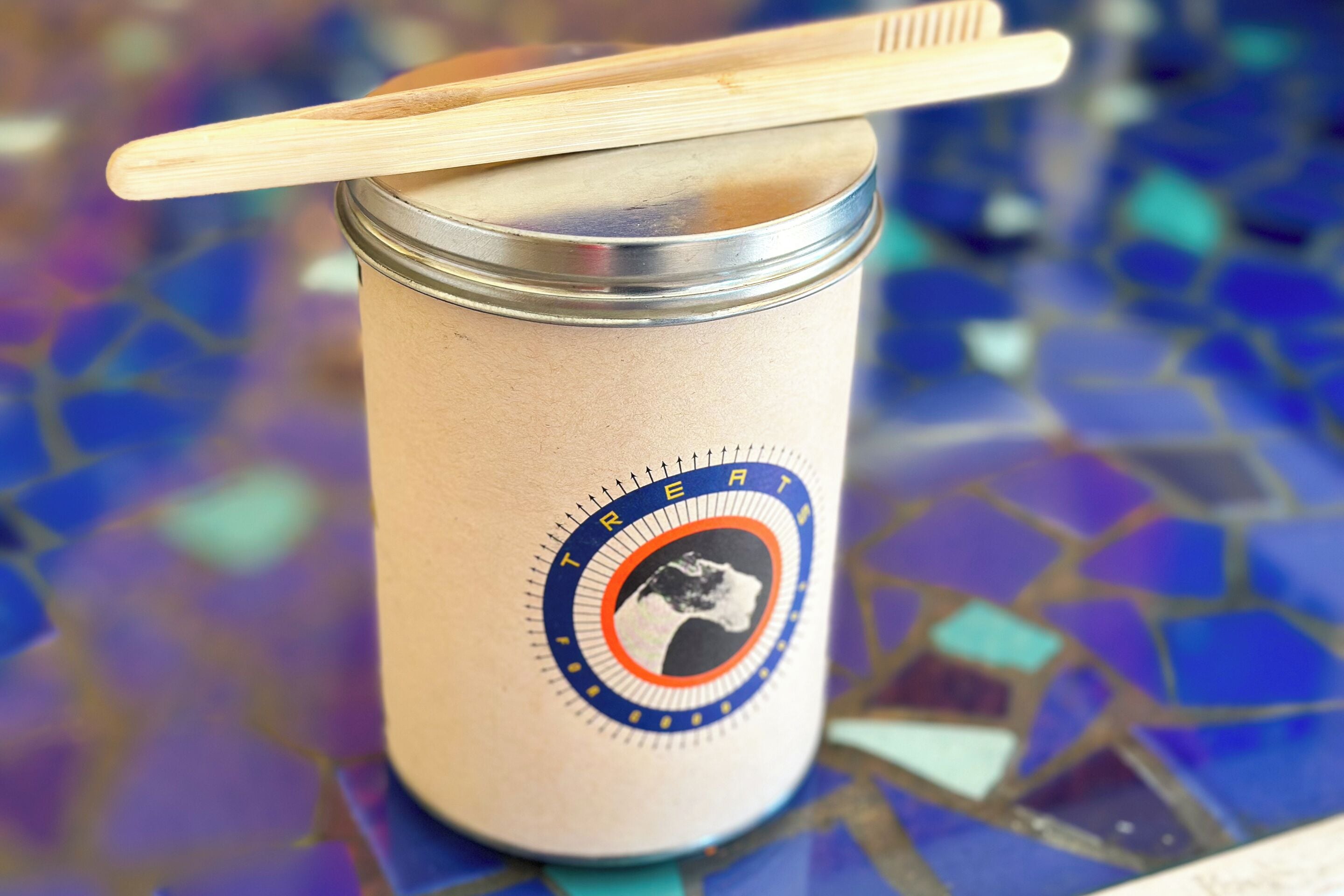 A jar with a wooden spoon on top, labeled "TREAT" with a circular logo.