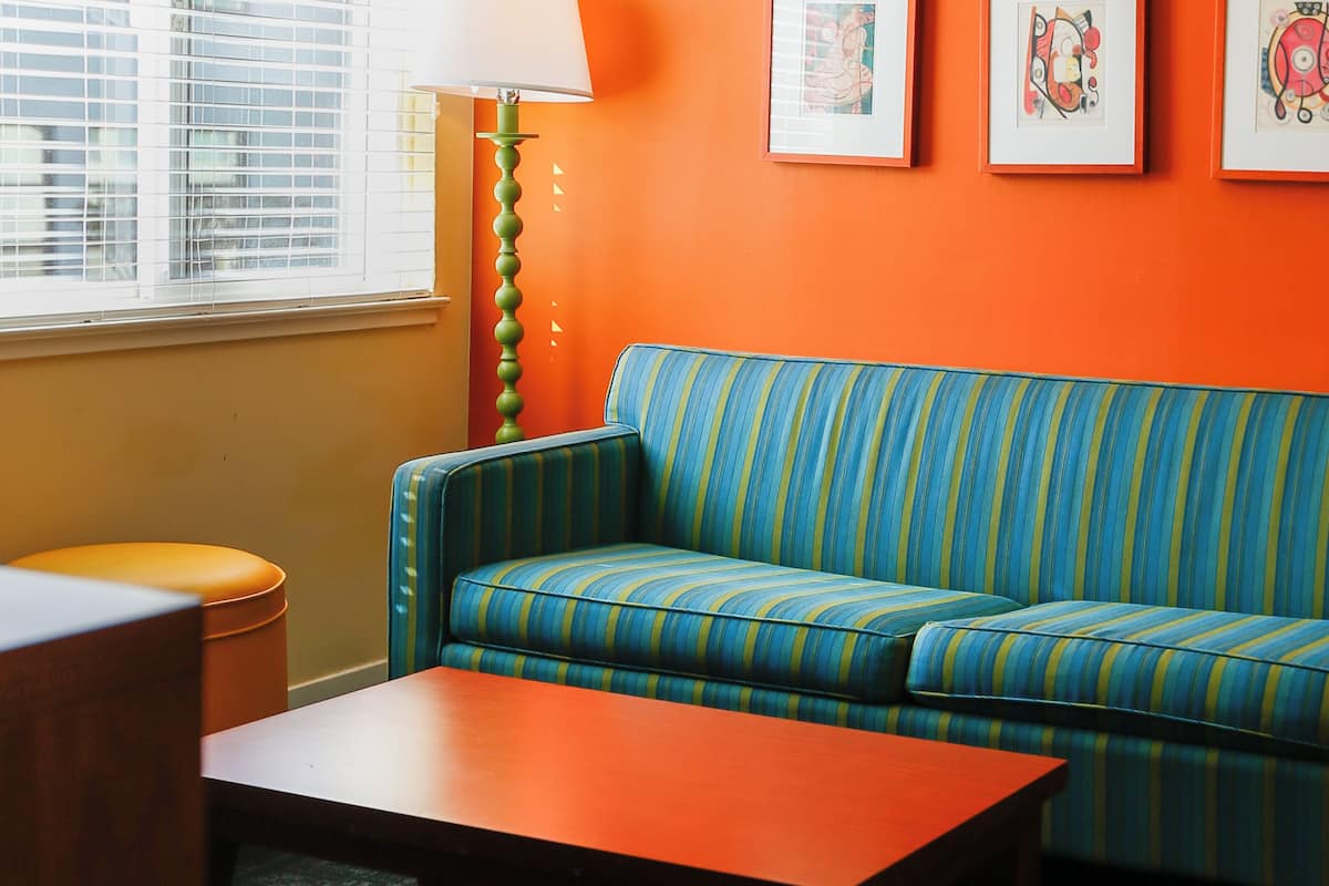 A room with a striped sofa, a wooden coffee table, a lamp, and framed artwork on the wall.
