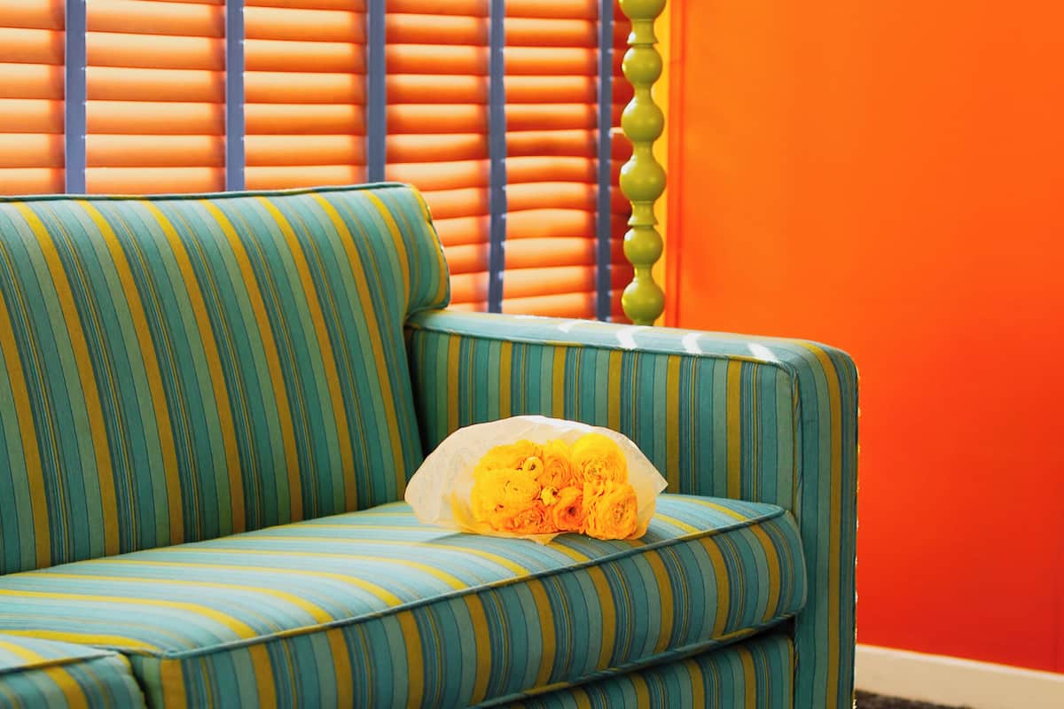 A striped sofa with a bouquet of yellow flowers.