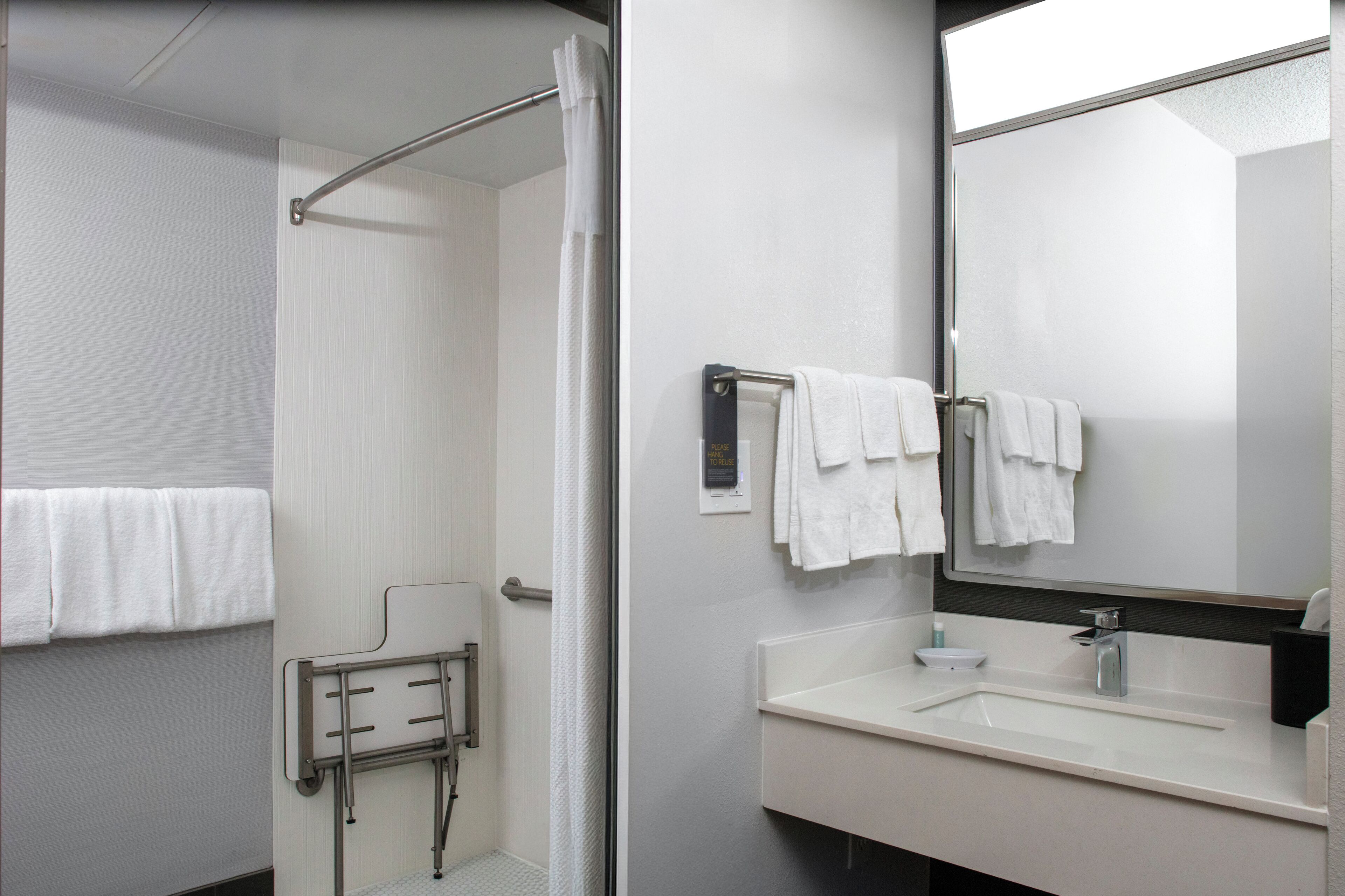Un baño moderno con ducha, lavamanos y espejo.