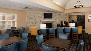 A hotel room with a dining area, a fireplace, a flat-screen TV, and a kitchen counter. - Residence Inn by Marriott Richmond Northwest (Richmond)