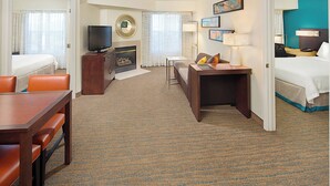 A hotel room with a bed, a desk, a television, a fireplace, and a dining area. - Residence Inn by Marriott Richmond Northwest (Richmond)