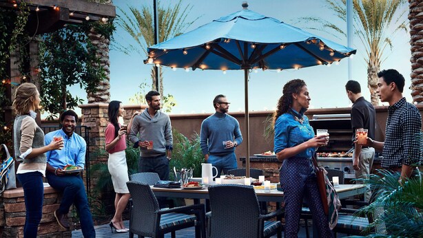 An outdoor patio area with tables and chairs, a grill, and string lights. - Residence Inn by Marriott Richmond Northwest (Richmond)