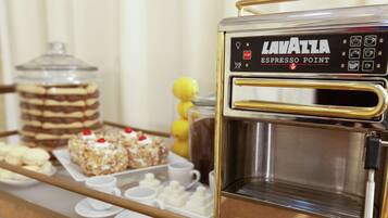 A coffee machine labeled "Lavazza Espresso Point" with a tray of pastries and cups.