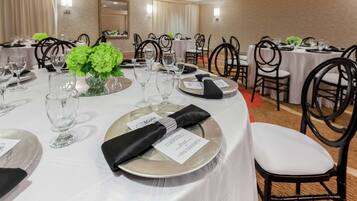 Un salón de banquetes con mesas redondas dispuestas para comer, cada una con menú, vasos y cubiertos.
