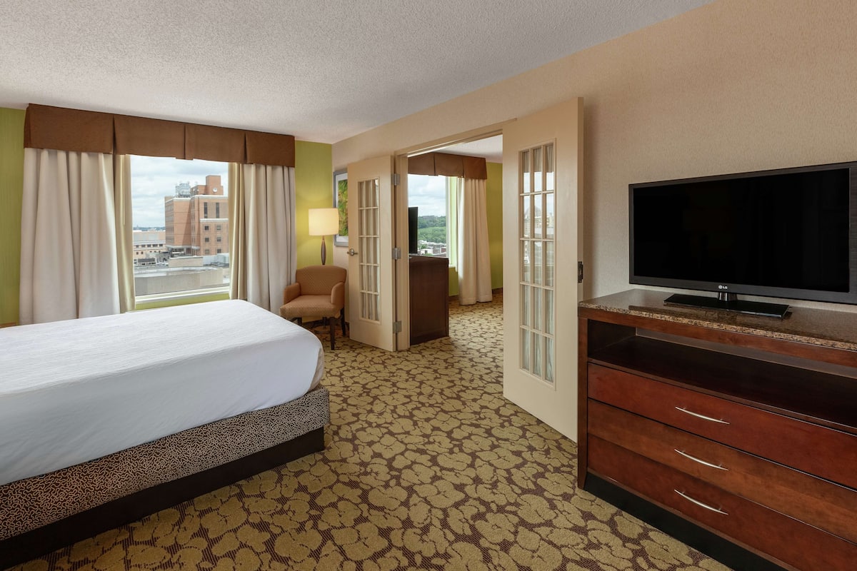 A hotel room with a bed, a TV, a desk, and a chair.
