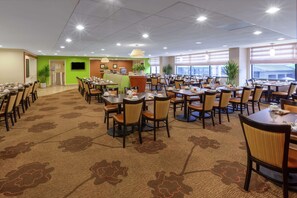 A spacious dining area with multiple tables and chairs, a reception desk, and large windows providing natural light. - Hilton Garden Inn Pittsburgh University Place (Pittsburgh)