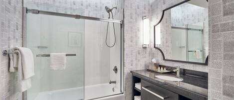 A modern bathroom with a glass-enclosed shower, a vanity with a sink, and a large mirror.