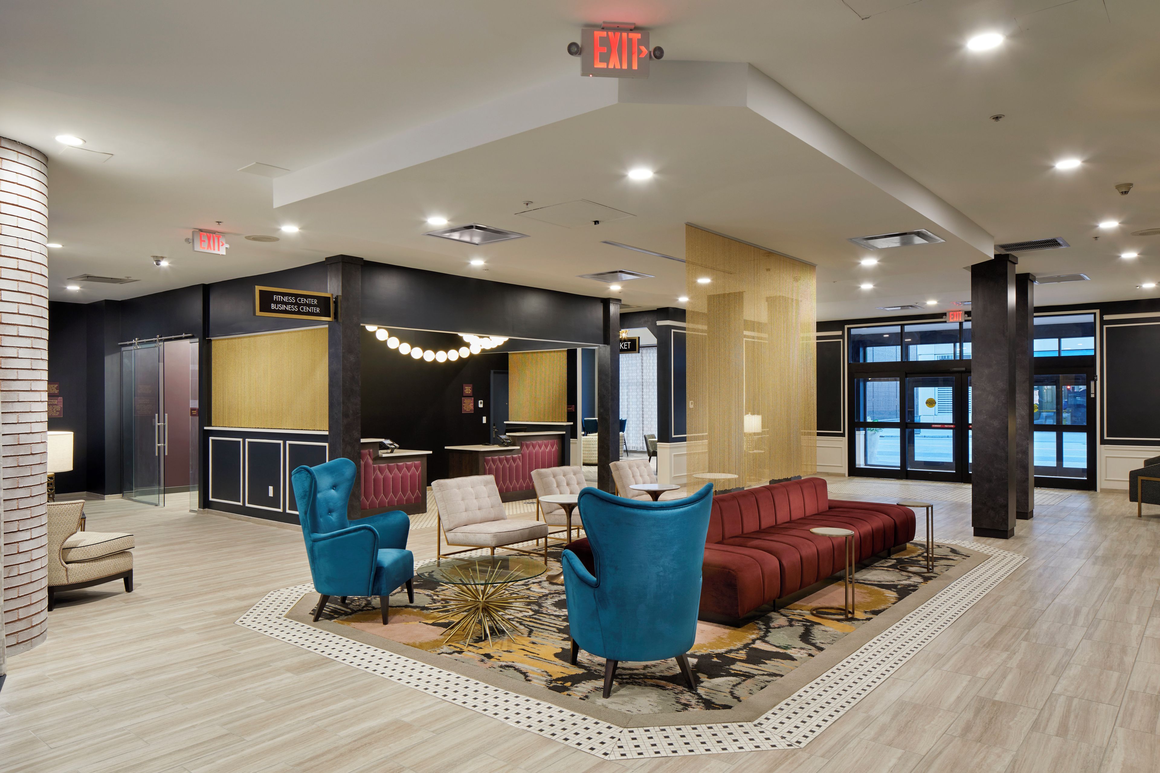 A lobby with a reception desk, seating area, and an exit sign.