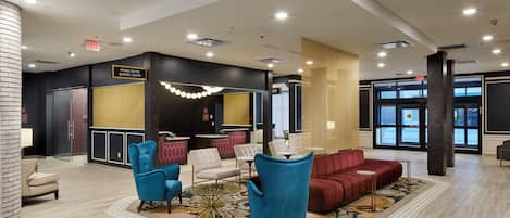 A lobby with a reception desk, seating area, and an exit sign.