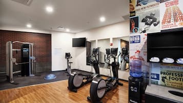 A gym with exercise equipment, a brick wall, and a mirror.