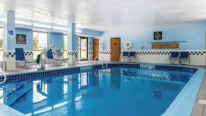 Una piscina con borde de azulejos azules, un elevador de piscina y un cartel de prohibido bucear.