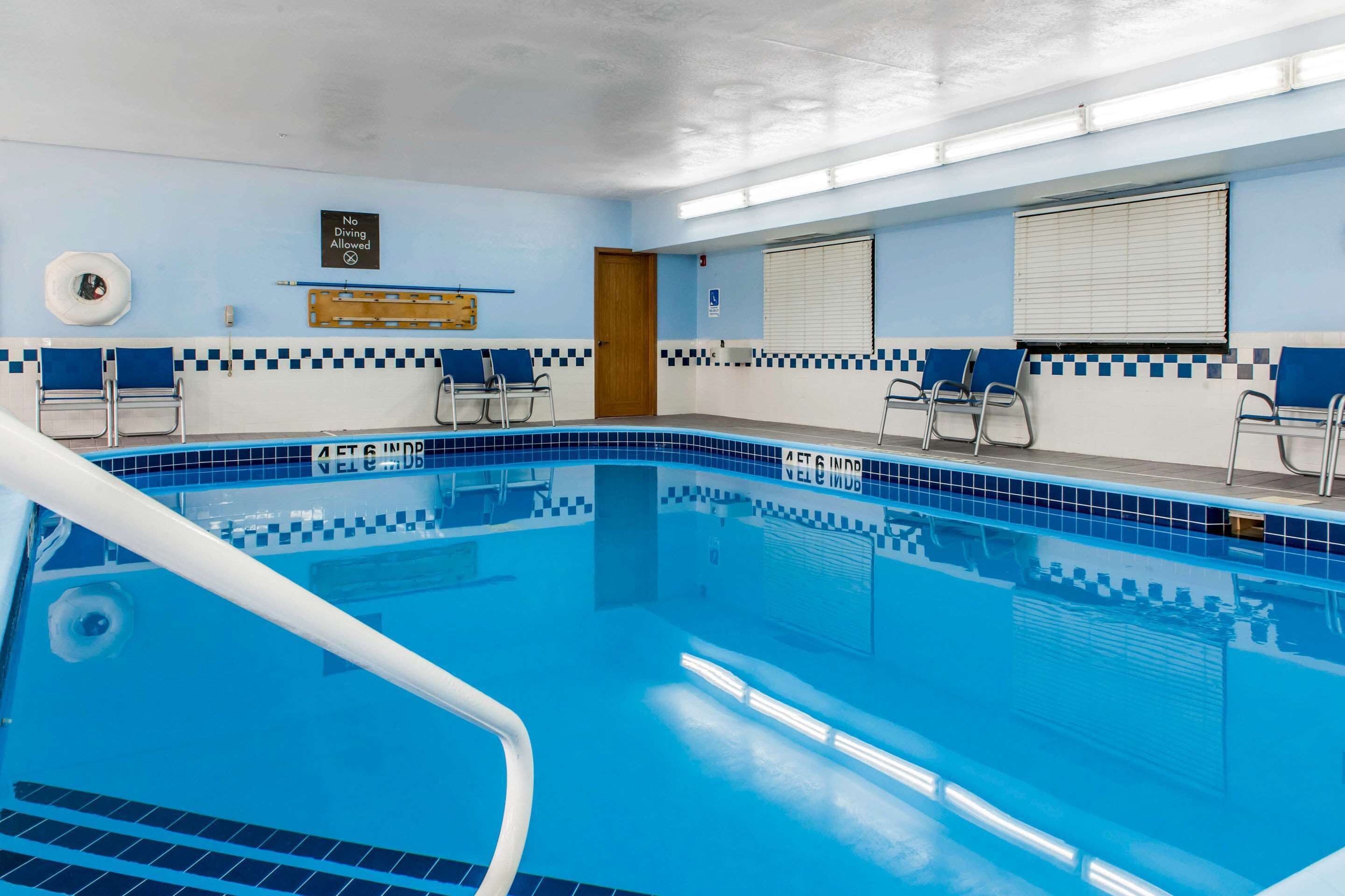 A swimming pool with blue tiles, a no diving sign, and a door.