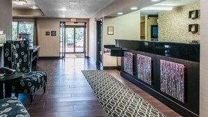 Un vestíbulo de hotel con una recepción, asientos estampados y una alfombra con diseño.