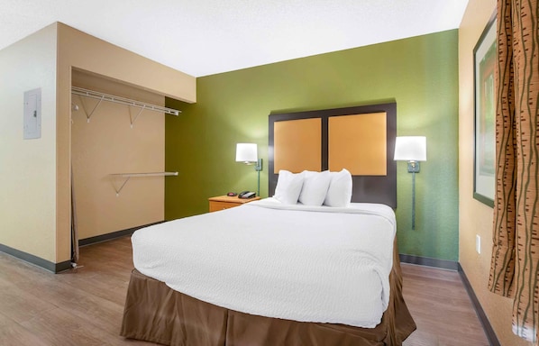 A hotel room with a large bed, bedside lamps, a nightstand, and a wardrobe. - Extended Stay America Select Suites - Jacksonville - Baymeadows (Jacksonville)