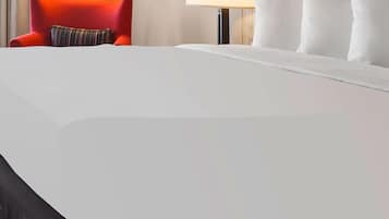Una habitación de hotel con una cama grande, un sillón rojo y una lámpara.