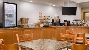 Une cuisine moderne et élégante, dotée de plans de travail en granit, de meubles en bois et d’un coin bar pour prendre le petit-déjeuner.