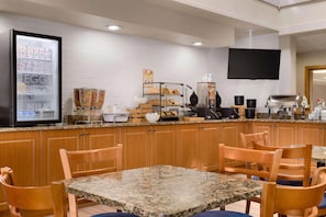 A clean, modern kitchen with granite countertops, wooden cabinets, and a breakfast bar area. - Country Inn & Suites by Radisson, Mishawaka - South Bend (Mishawaka)