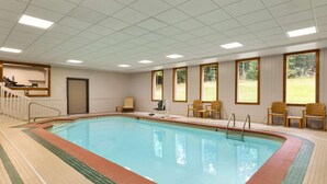 Une piscine avec une terrasse carrelée, un vestiaire et un espace détente comprenant des chaises et une table.