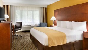 A hotel room with a large bed, a desk with a computer, an air conditioning unit, and a television. - Country Inn & Suites by Radisson, Mishawaka - South Bend (Mishawaka)