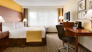 A hotel room with a bed, desk, chair, TV, and artwork on the wall. - Country Inn & Suites by Radisson, Mishawaka - South Bend (Mishawaka)