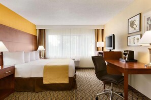A hotel room with a bed, desk, chair, TV, and artwork on the wall. - Country Inn & Suites by Radisson, Mishawaka, IN (Mishawaka)