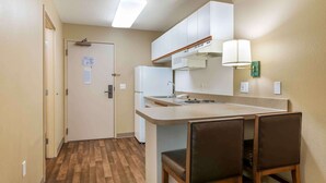 A compact kitchen with a refrigerator, a sink, and a small dining area with two chairs. - Extended Stay America Suites Kansas City Overland Pk Nall Av (Overland Park)