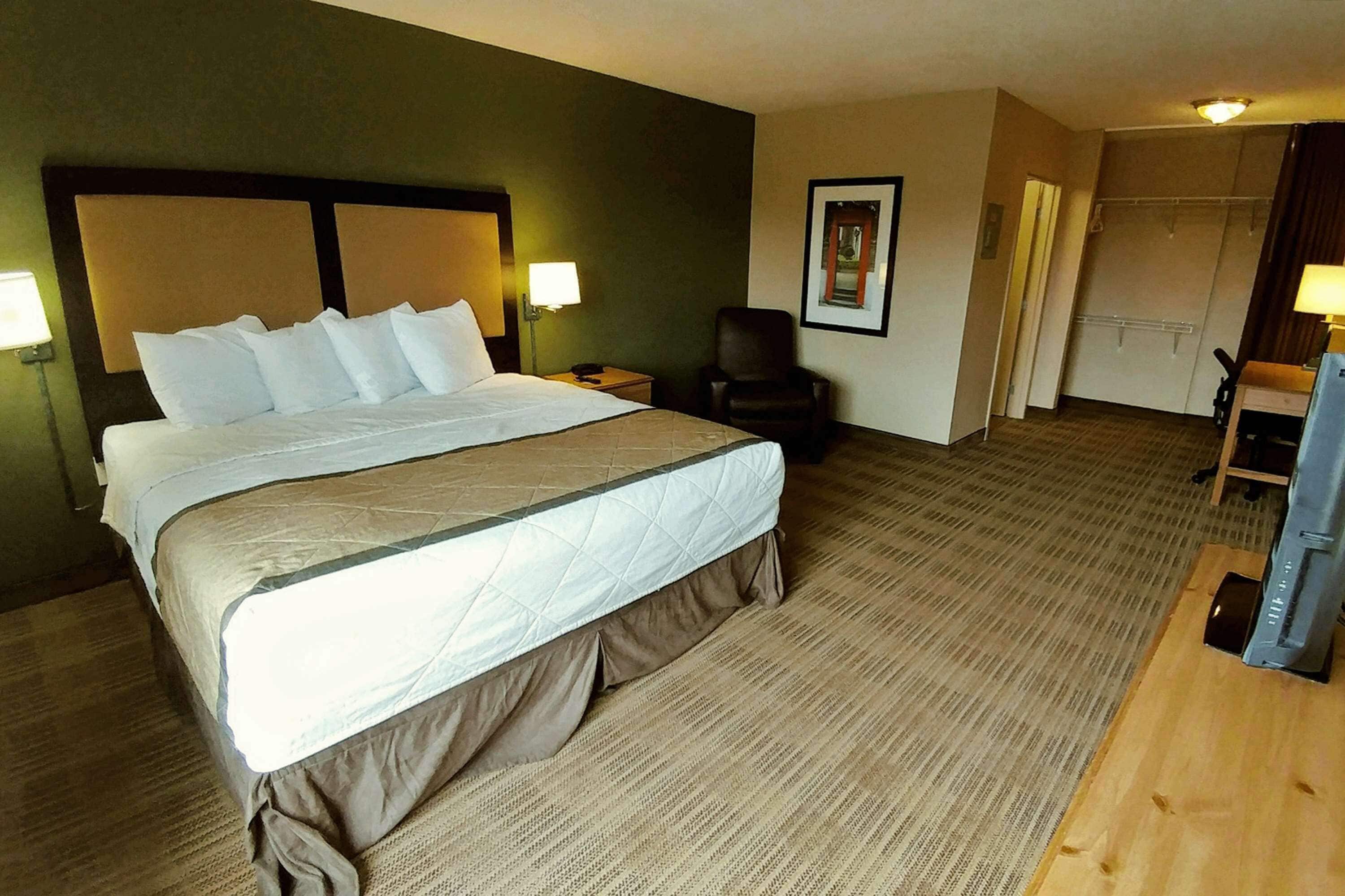 Een hotelkamer met een groot bed, een stoel, een bureau en een televisie.