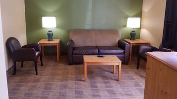 A living room with a brown sofa, two armchairs, a coffee table, and two lamps on side tables.
