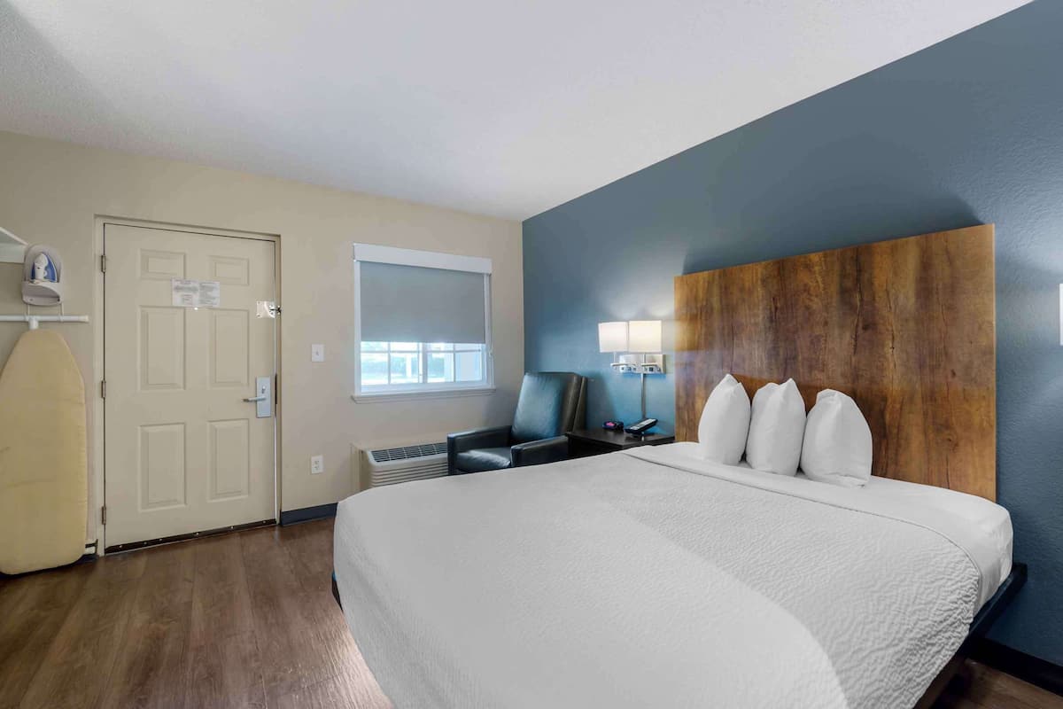 Habitación de hotel con una cama grande, un escritorio con silla, una ventana y una puerta.