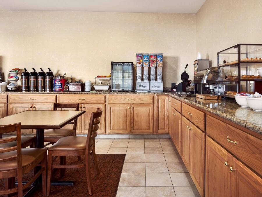 Una cocina con armarios de madera, encimera de granito, estación de café y zona de buffet.