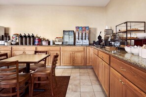 A kitchen with wooden cabinets, a granite countertop, a coffee station, and a buffet area.