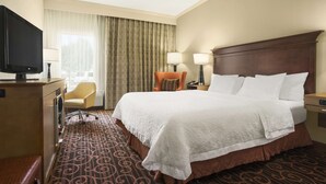 A hotel room with a large bed, a television, a desk, and a chair.