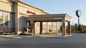A Hampton Inn with a 'Welcome' sign, a covered entrance, and a parking lot.