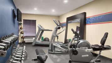 A gym with treadmills, elliptical machines, and weight benches.