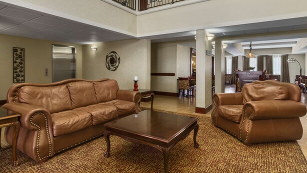 A spacious lobby with leather sofas, a wooden coffee table, and a patterned carpet.