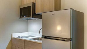 A kitchen with a stainless steel refrigerator, a microwave, and wooden cabinets. - Suburban Studios Raleigh - Crabtree Valley (Raleigh)
