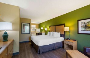 Una habitación de hotel con una cama, mesitas de noche, un escritorio, una silla y una lámpara.