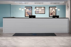 A reception desk with two laptops, framed posters on the wall, and pendant lighting. - Coconut Malorie Resort Ocean City, an Ascend Collection Hotel (Ocean City)