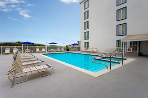 A swimming pool with lounge chairs and umbrellas, a building with multiple windows, and a clear sky. - Coconut Malorie Resort Ocean City, an Ascend Collection Hotel (Ocean City)