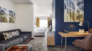 A hotel room with a sofa, a desk with a lamp, a bed, and artwork on the walls. - SpringHill Suites Tempe at Arizona Mills Mall (Tempe)