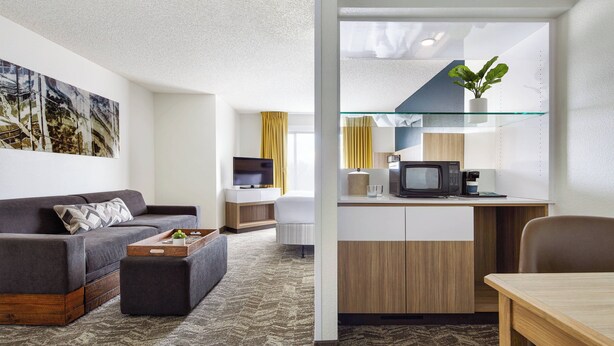 A modern hotel room with a living area, kitchenette, and a large window. - SpringHill Suites Tempe at Arizona Mills Mall (Tempe)