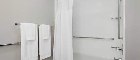 Un baño moderno con una bañera, una cortina de ducha y dos toallas colgadas en un perchero.