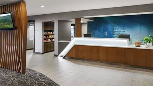 A modern reception area with a wooden reception desk, a wall-mounted TV, and a digital display with text. - SpringHill Suites Tempe at Arizona Mills Mall (Tempe)