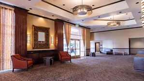 A spacious lobby with patterned carpet, two armchairs, a large mirror, and a reception desk. - Hampton Inn & Suites Salt Lake City Airport (Salt Lake City)