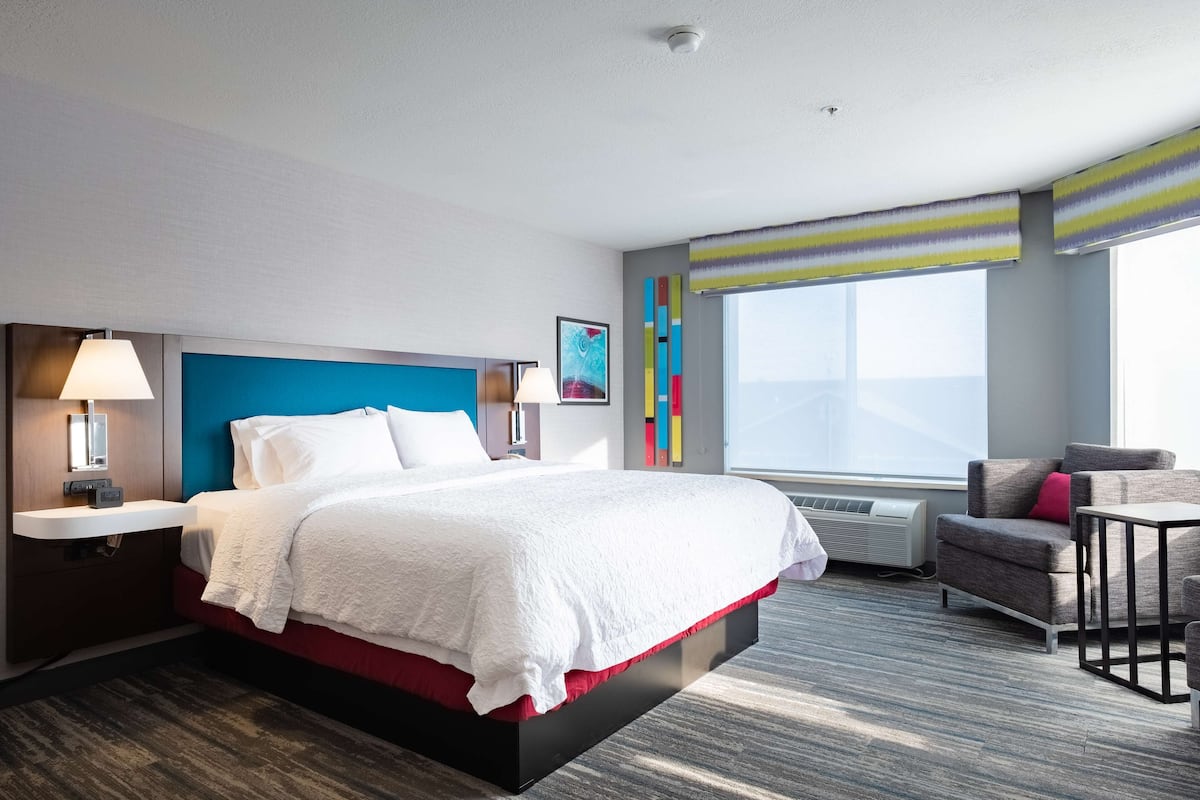 Ein modernes Hotelzimmer mit einem großen Bett, einem Schreibtisch, einem Stuhl und einem Fenster mit Blick.