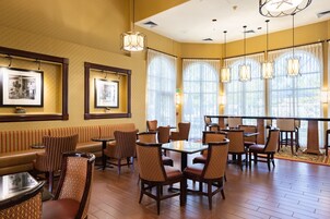 Un restaurante con piso de madera, asientos acolchados e iluminación colgante.